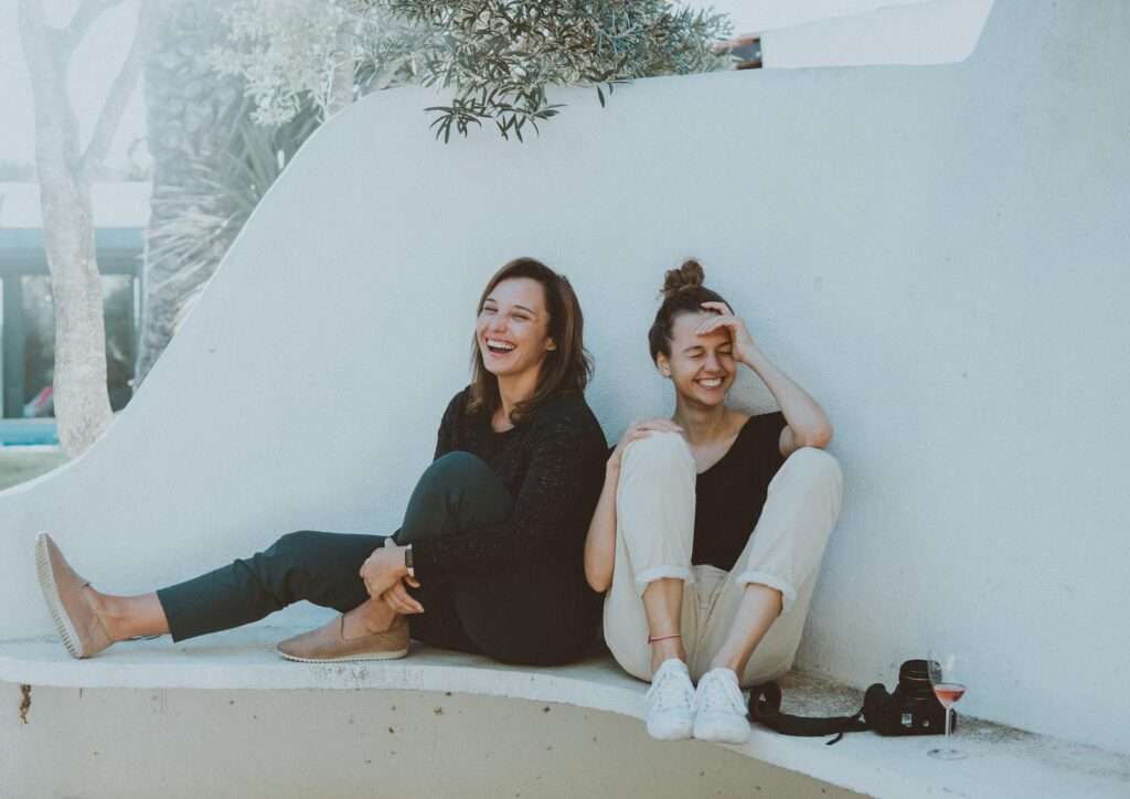 Two women laughing together outdoors, enjoying leisure time and friendship.