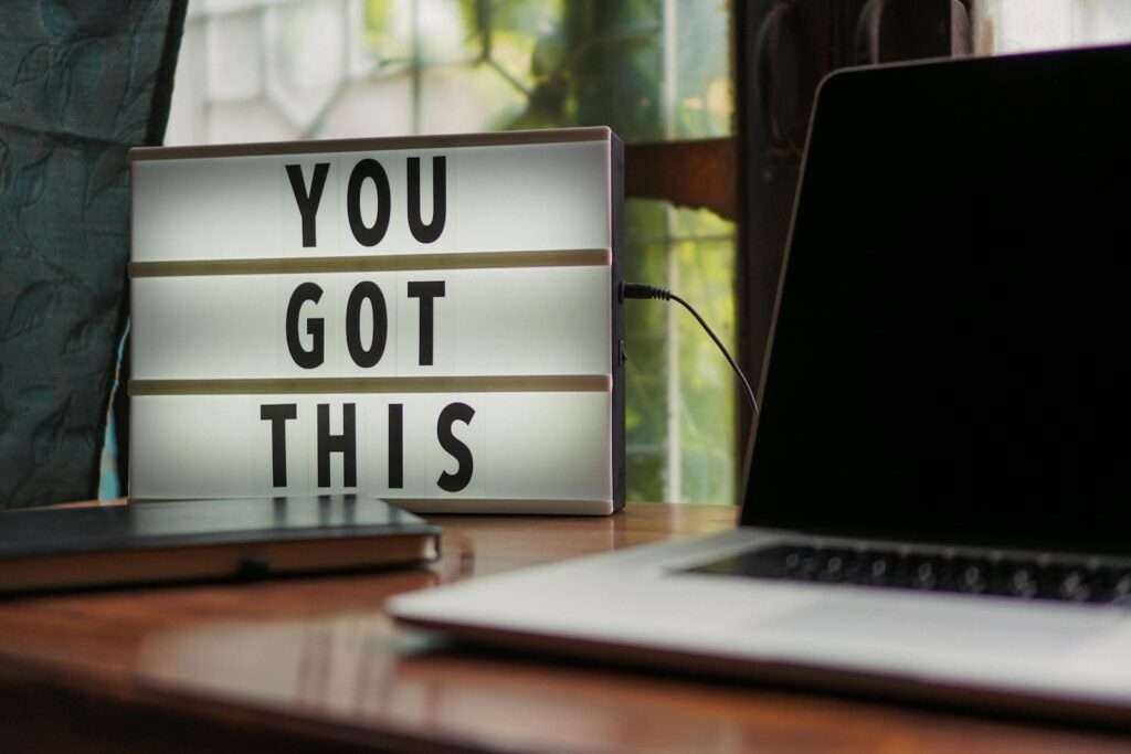 Lit sign with 'You Got This' alongside laptop on office desk.