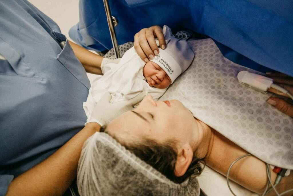 A mother cradling her newborn immediately after childbirth in a hospital setting.