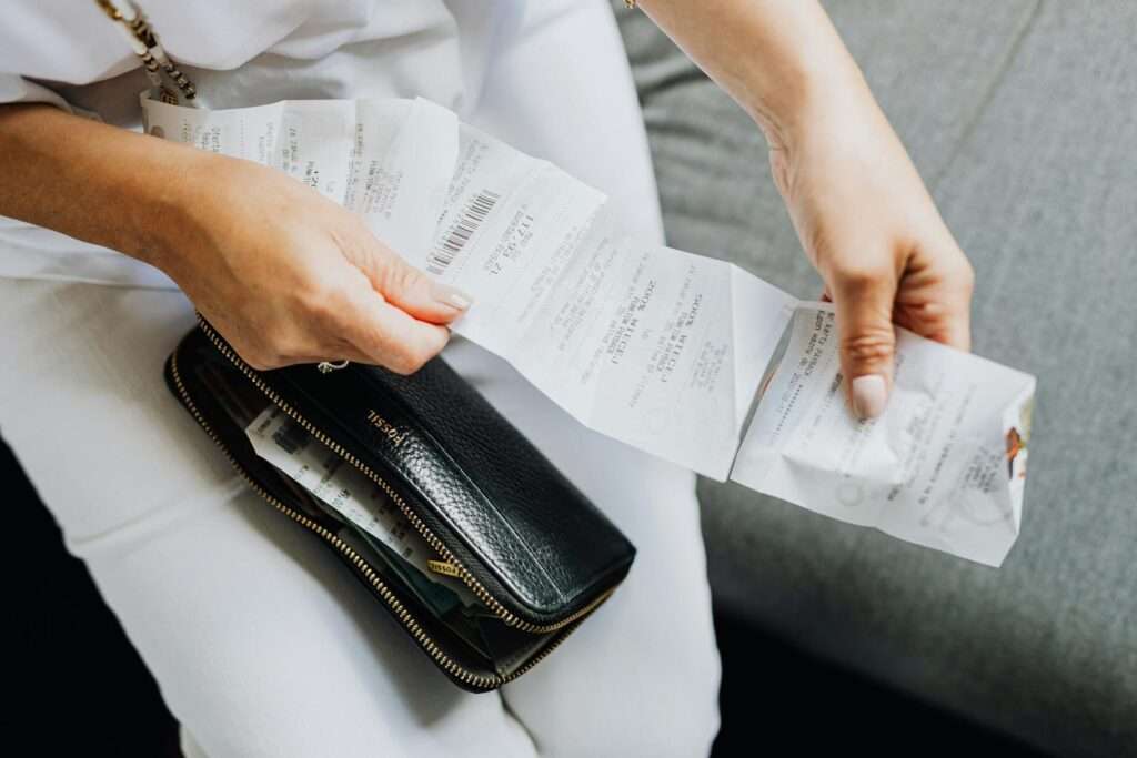 Close-up of a woman's hands managing multiple receipts taken from a black wallet.