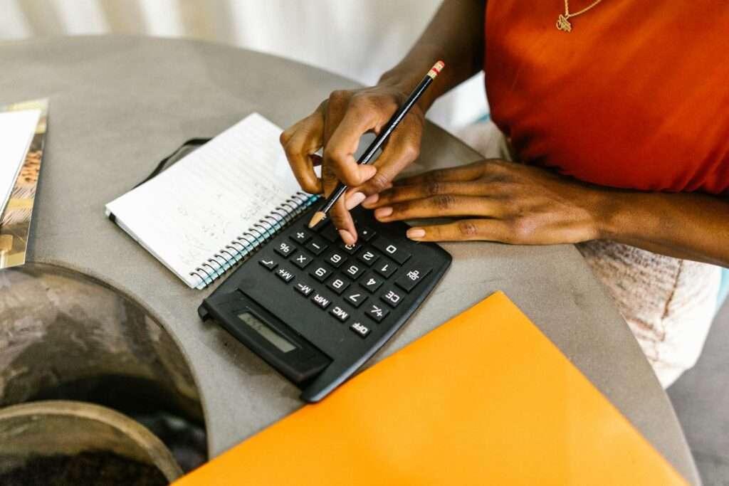 An African American woman using a calculator and notepad for budgeting.