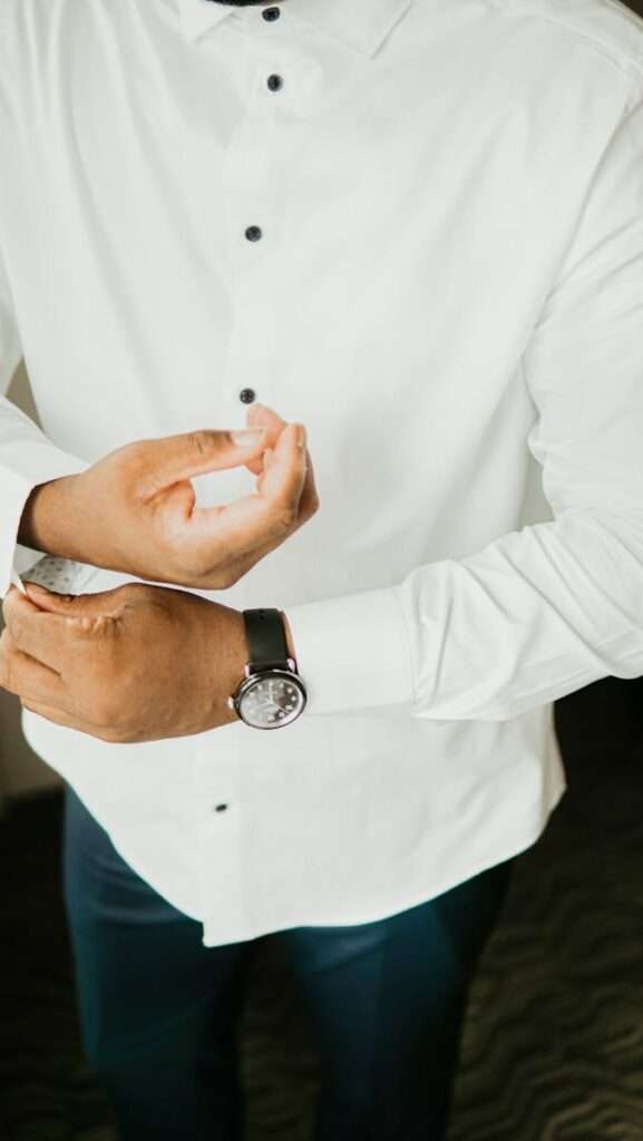 A groom adjusts his cufflinks, showcasing elegant attire for his wedding day.