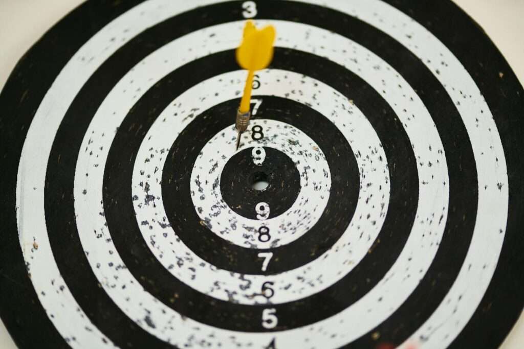 Close-up of a dart hitting the bullseye on a black and white target board symbolizing success.