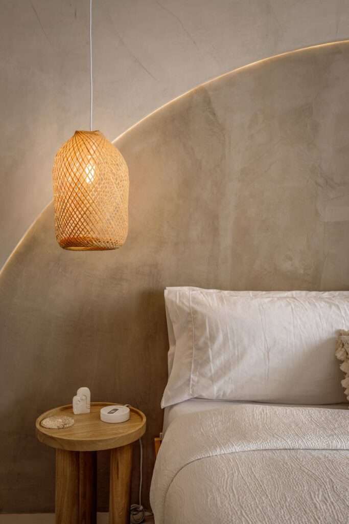 Elegant minimalist bedroom featuring woven lamp and soft white bedding.