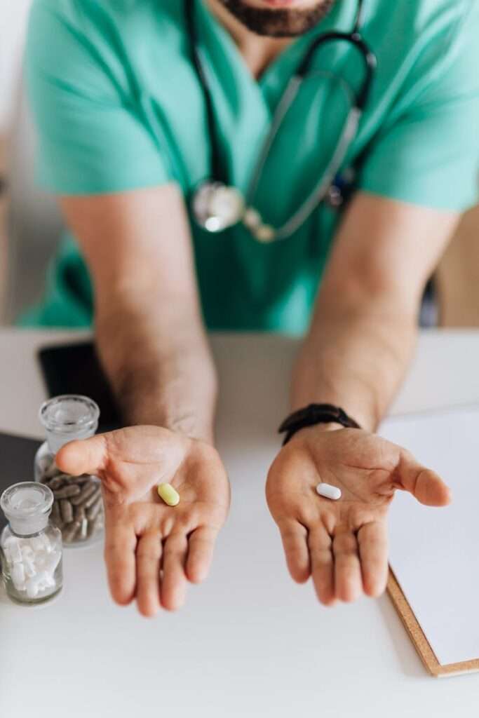 Close-up of a doctor holding out two pills, representing a choice in medication.