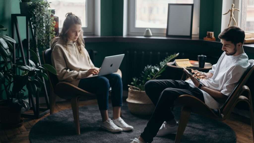 A couple working remotely in a stylish home office with plants and modern decor.