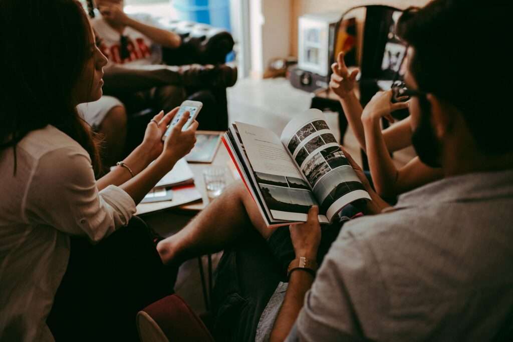 Casual group discussion with people reading a magazine and interacting indoors.