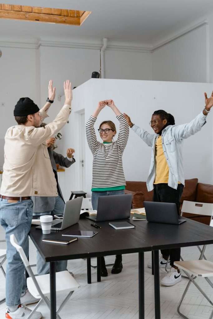 A multicultural group of professionals celebrating success in a modern office setting, emphasizing teamwork and collaboration.